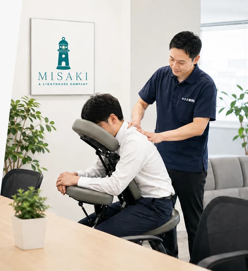 オフィスで施術用の椅子に座った従業員が、担当者から肩まわりのケアを受けているイメージ