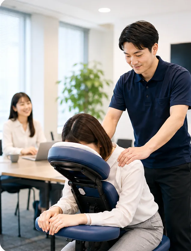 オフィスの会議室で、施術者が椅子に座った従業員の肩まわりをケアしているイメージ