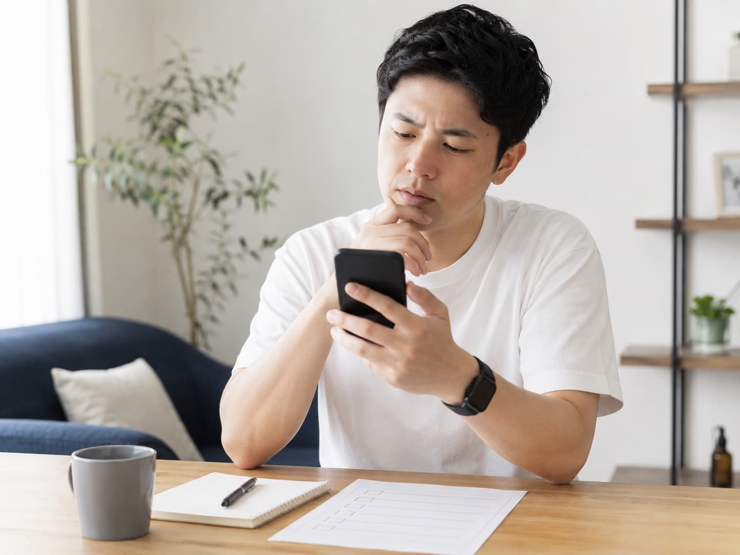 自宅のソファでスマートフォンを手に事故後の手順を確認している男性