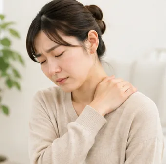 肩に手を当てて痛みを気にしている女性