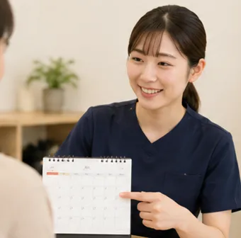 カレンダーを指しながらご来院の流れを案内する様子