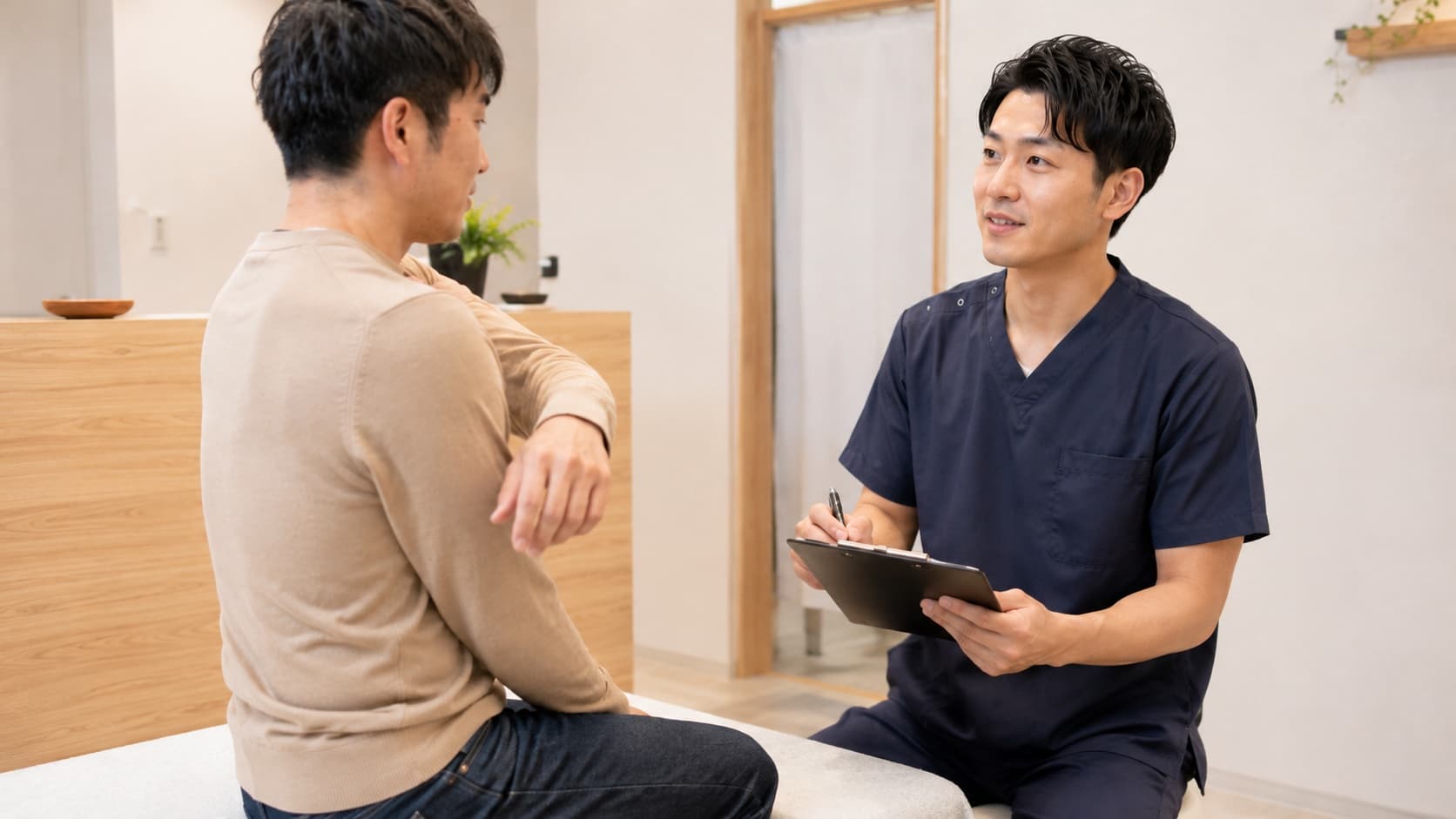 施術ベッドのそばで患者の首まわりの状態を確認している様子