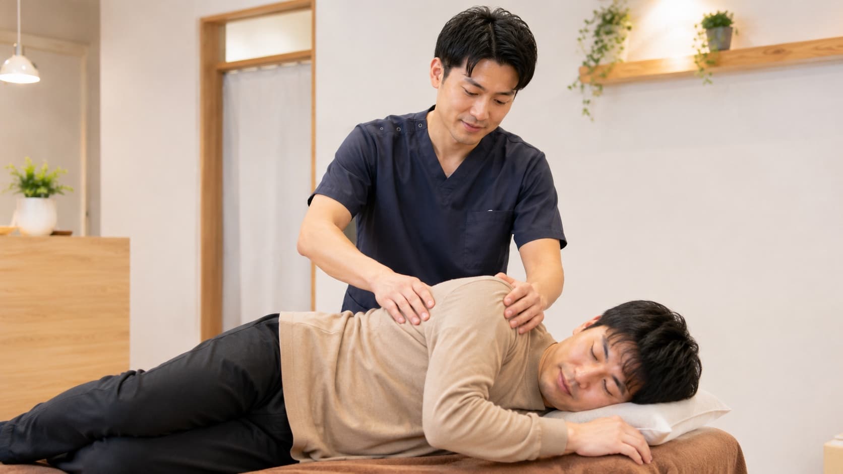 施術ベッドで患者の背中に手を当てて施術している様子