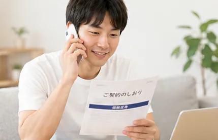 電話をしながら保険のしおりを確認している男性